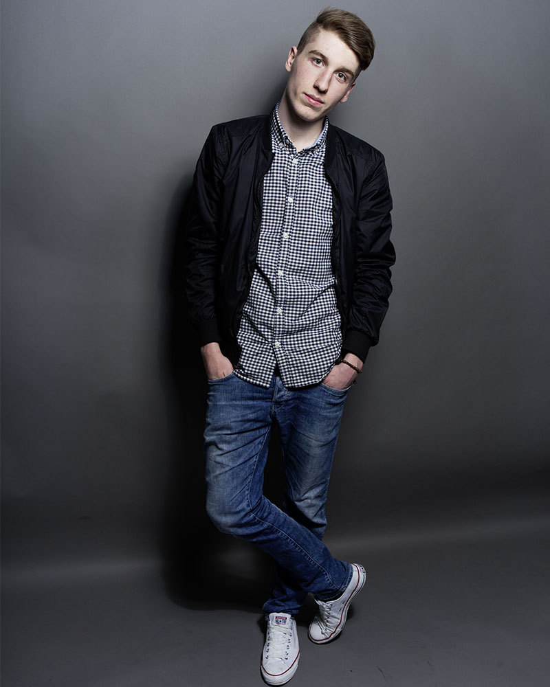 Portraitbilder in Northeim von einem jungen Mann in Jeans und kariertem Hemd vor grauen Hintergrund