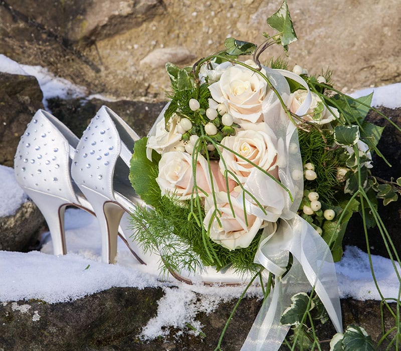 Hochzeitsfotografie im Detail mit Strauß und Schuhen im Schnee