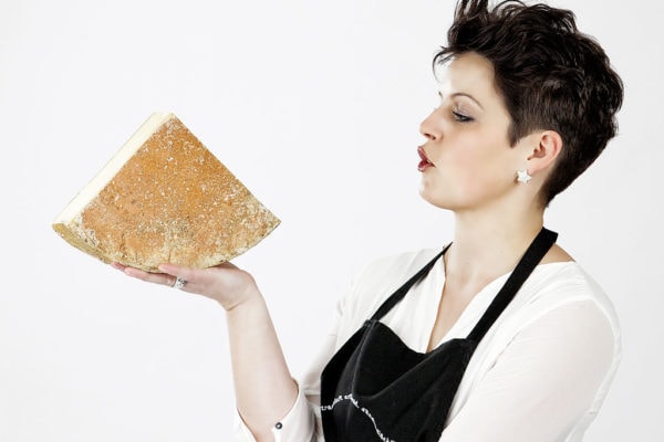 Produktfotografie, Dame in schwarzer Schürze mit Käse in der Hand
