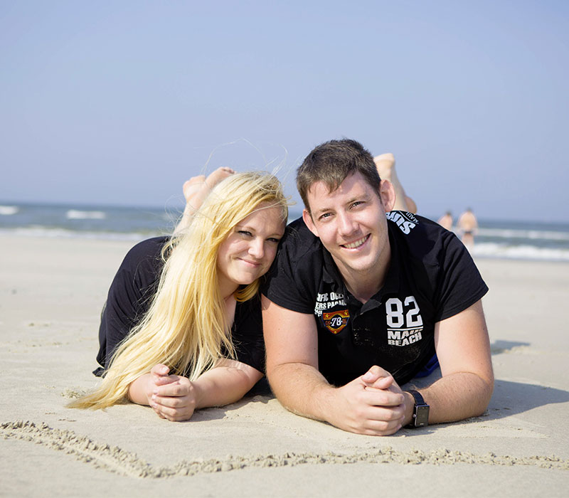 Familienfotos eines Paares am Strand fröhlich in der Sonne